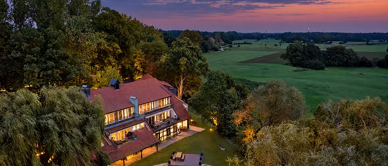 Luftbild der Schlossresidenz im Park, Wiesen und Teich im Abendlicht